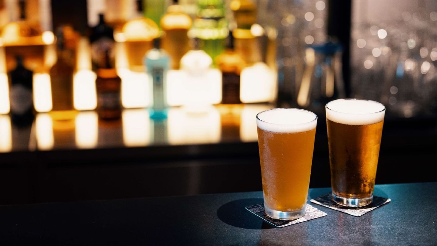 Two glasses of beer on a bar counter, promoting the happy hour offer at Sunway Hotel Pyramid