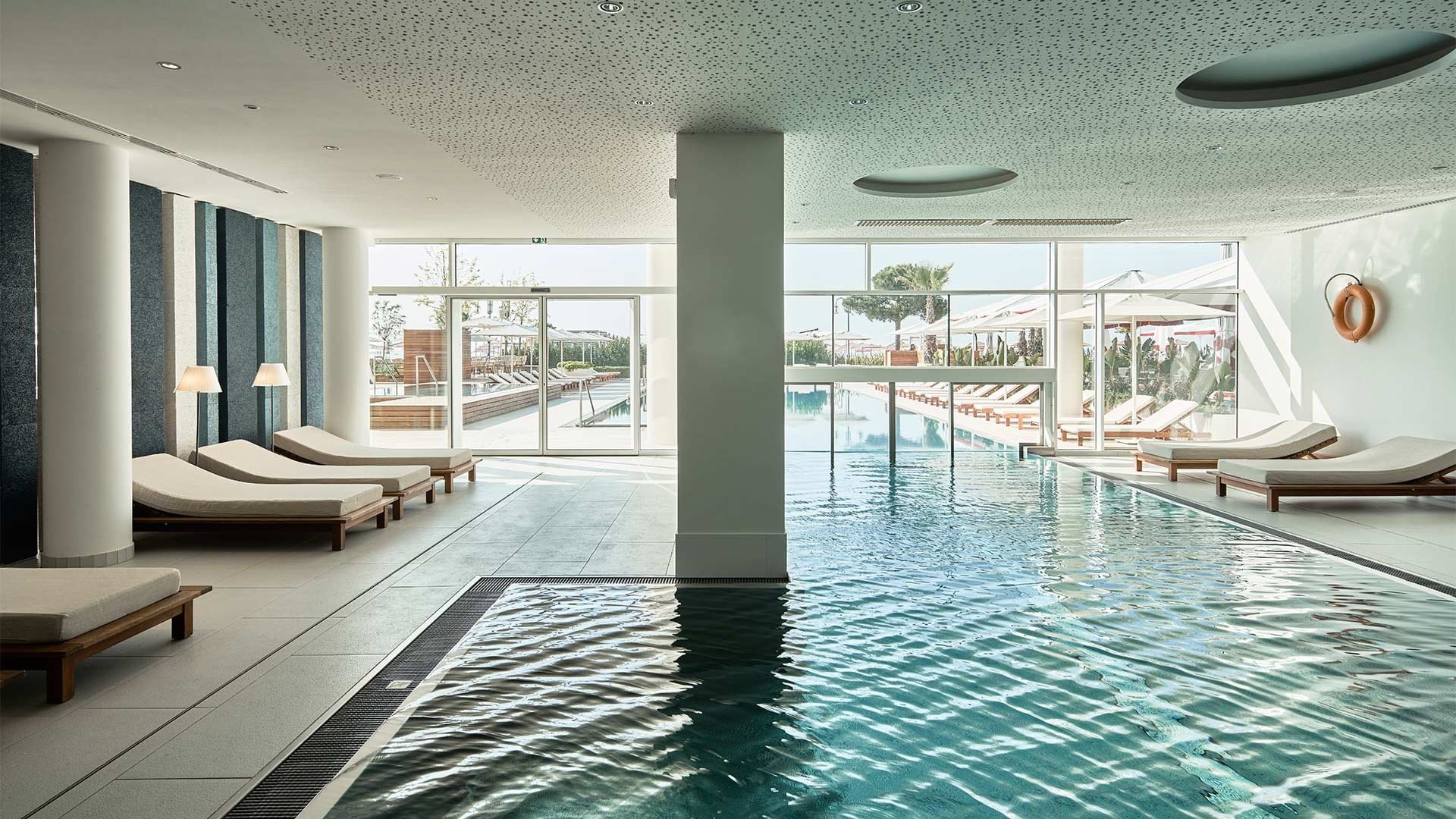 Moderner Poolbereich mit Liegen und Glaswänden bei Falkensteiner Hotel & Spa Jesolo