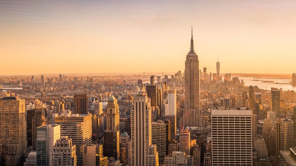 Aerial view of city skyscrapers surrounding a tall spire under a hazy sky near Warwick Grand Place Brussels
