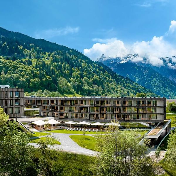 Falkensteiner Family Resort Lido with outdoor seating in front of a lush green mountainous landscape