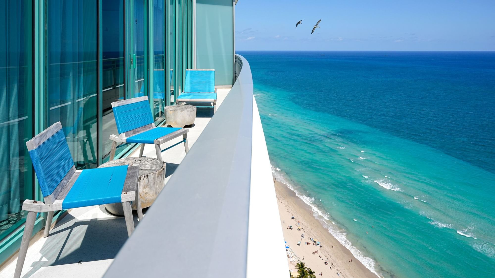 Balcony view from high-rise with blue chairs in Corner Ocean Suite at Diplomat Beach Resort