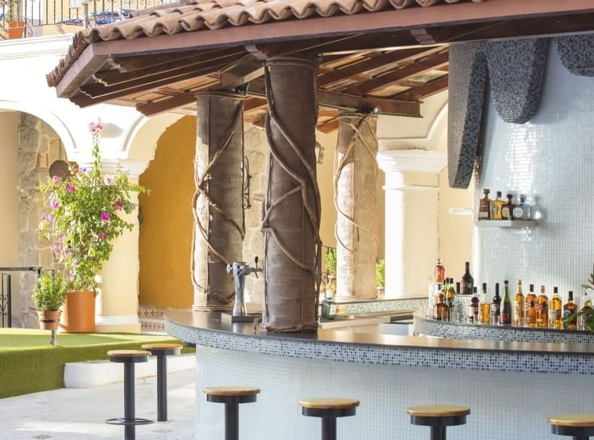Outdoor poolside bar with mosaic tile counter, wrapped columns, and tropical flowers at Playa Los Arcos Puerto Vallarta 2023