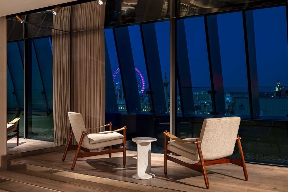 Suite living area with night views of the city skyline and the London Eye at The Londoner Hotel