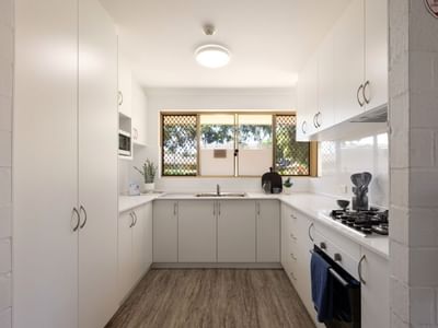 Modern kitchen with white cabinets, stove, and wooden floor at UniLodge Vickery House.