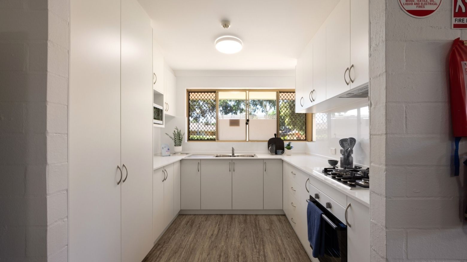 Modern kitchen with white cabinets, stove, and wooden floor at UniLodge Vickery House.
