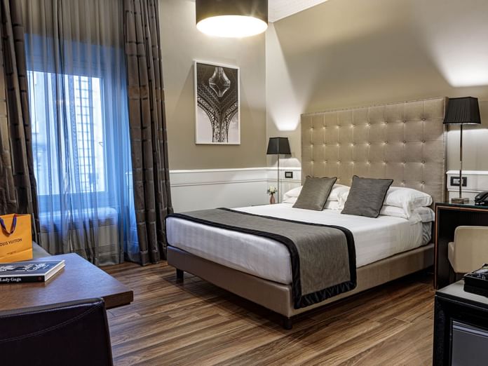 Cozy Deluxe Room with a king bed, chic decor, desk, sheer-curtained windows, and elegant lighting at The Independent Suites