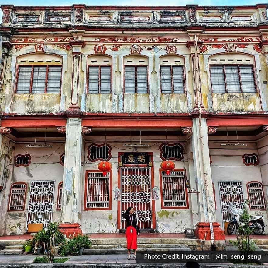 A woman was taking a picture in front of the old Chinese architectural building - Lexis Suites Penang