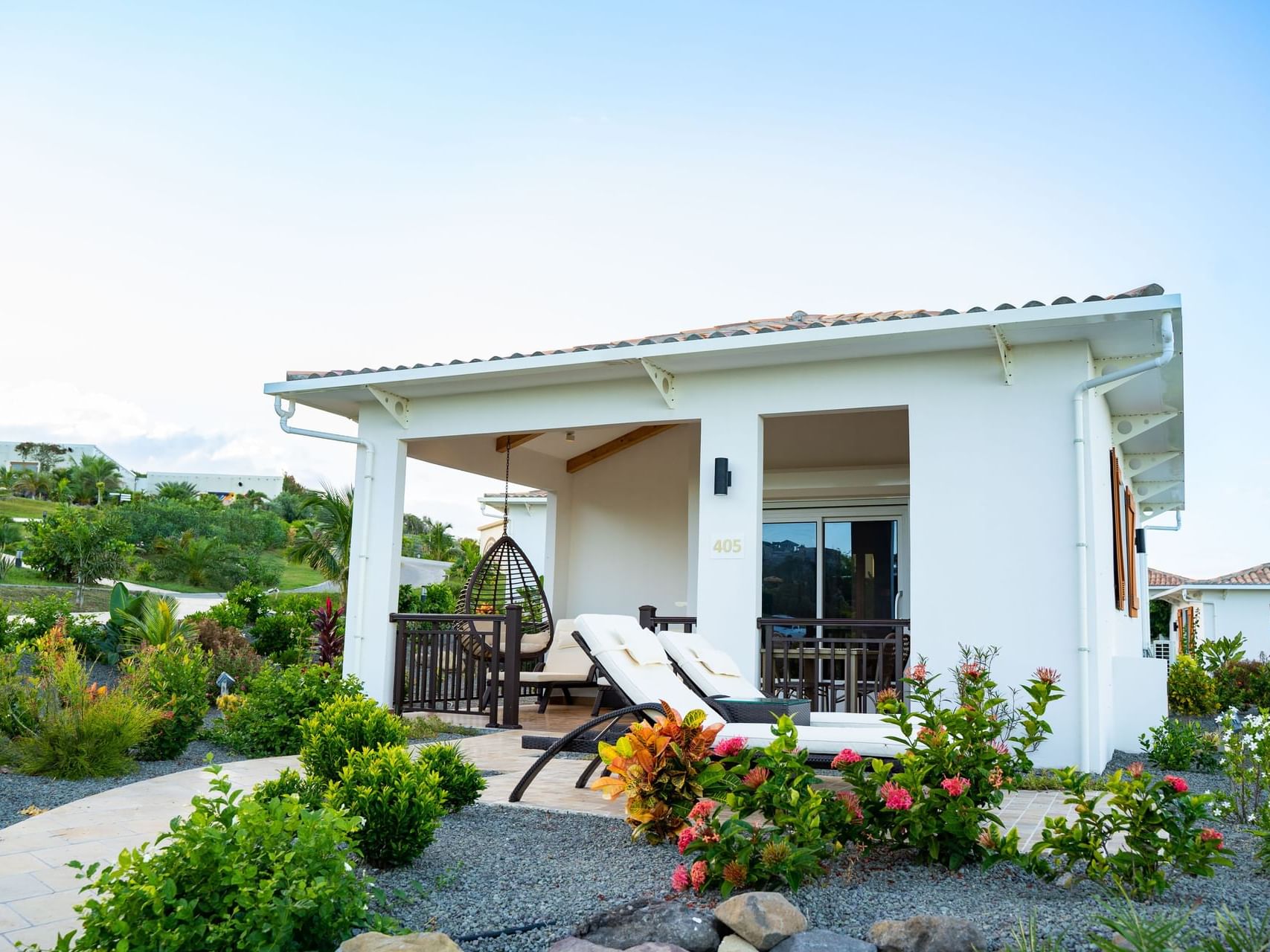 Two-Bedroom Cottage with a hanging chair, sun loungers, and surrounding garden greenery at Golden Rock Resort