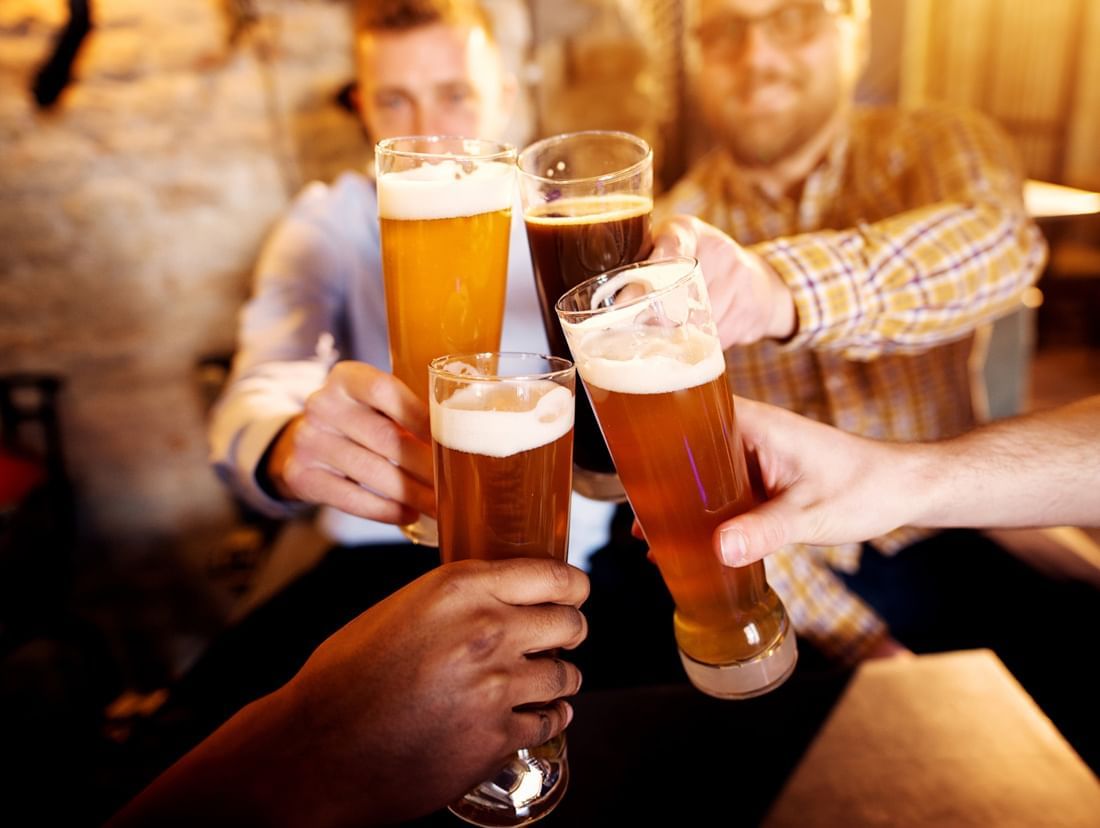 Four friends toasting beers in Frankie Farrell's Pub and Grill at Lake Buena Vista Resort Village & Spa