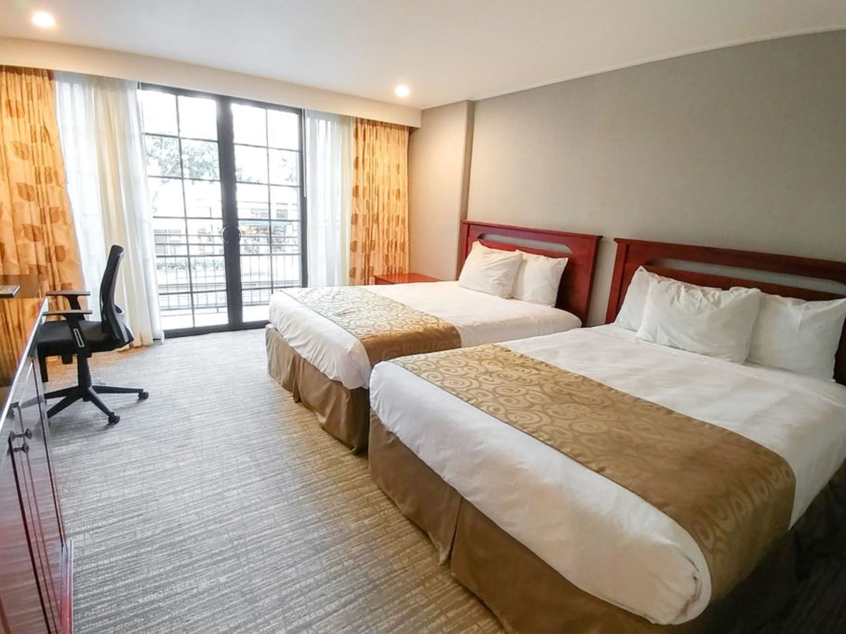 Studio with two double beds, desk, chair, and balcony access at Polynesian Residences in Honolulu