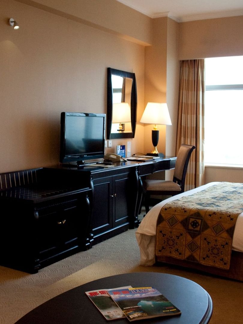 TV facing a bed with a work desk by the window in Family Suite Celebrity 2 at Celebrity International Grand Hotel