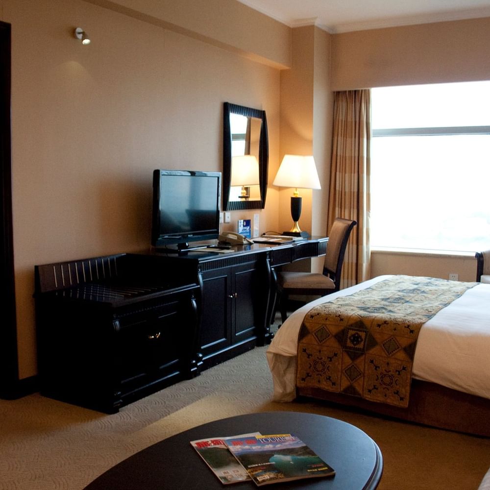TV facing a bed with a work desk by the window in Family Suite Celebrity 2 at Celebrity International Grand Hotel