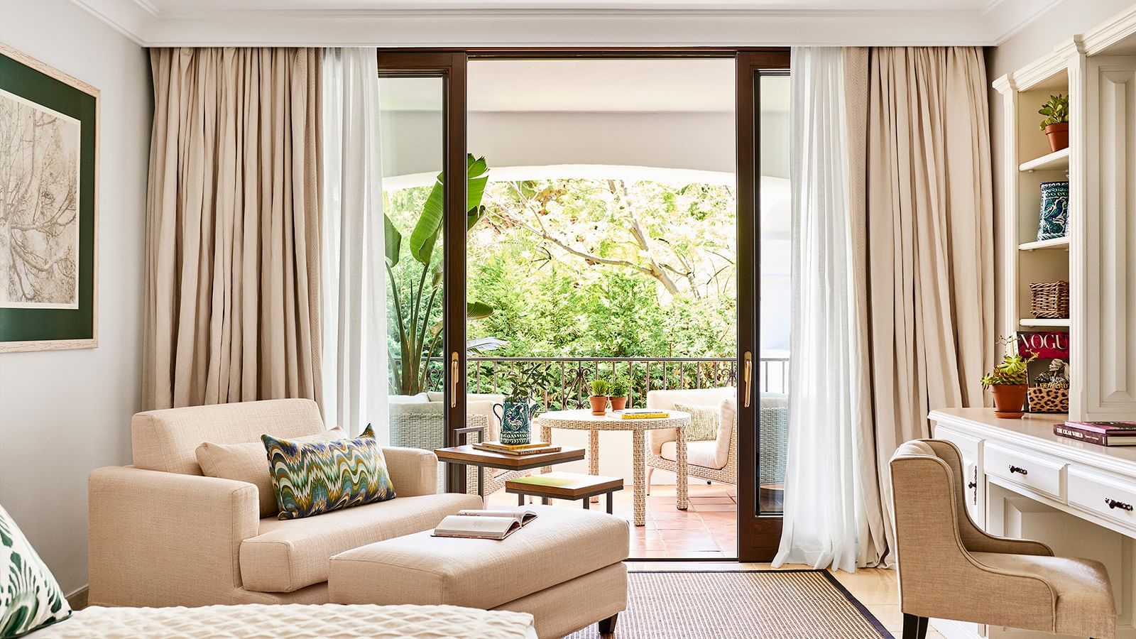 Living area with a sofa and armchairs by sliding doors that open to a covered patio at the Marbella Club