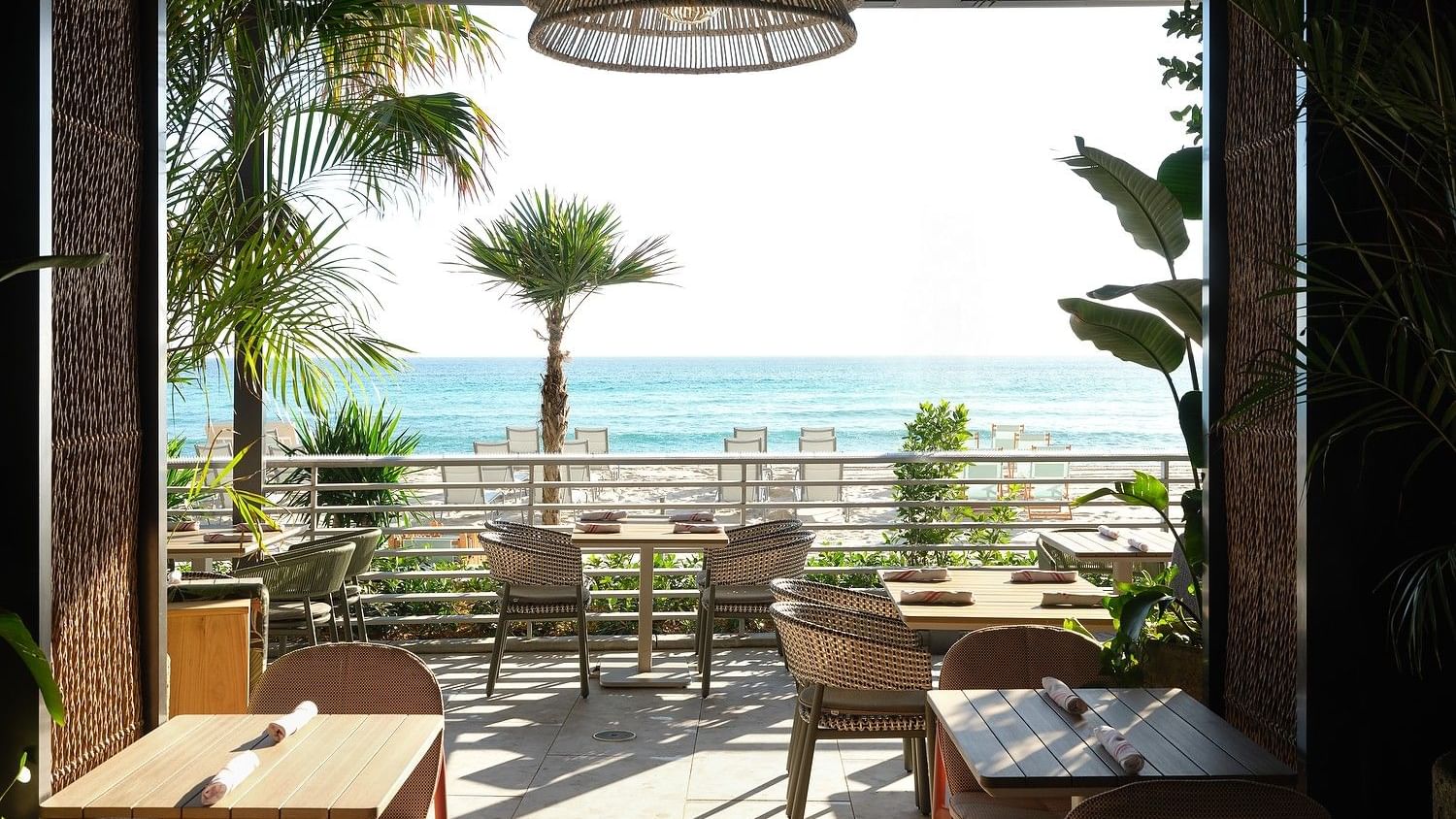 Open-air beachfront restaurant with ocean views, natural textures, and relaxed seating.
