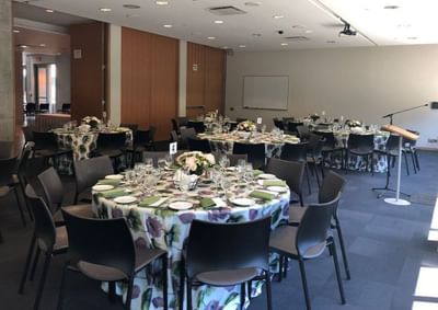 Event space with several round tables covered in floral tablecloths at the Schulich School of Business.