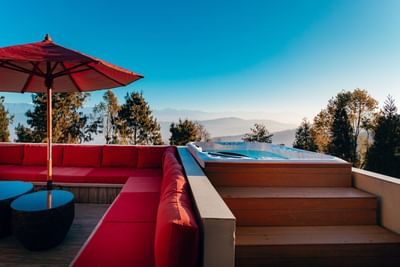 Terraces Presidential Suite outdoor patio with red sofa, umbrella, and Jacuzzi at The Terraces Resort & Spa