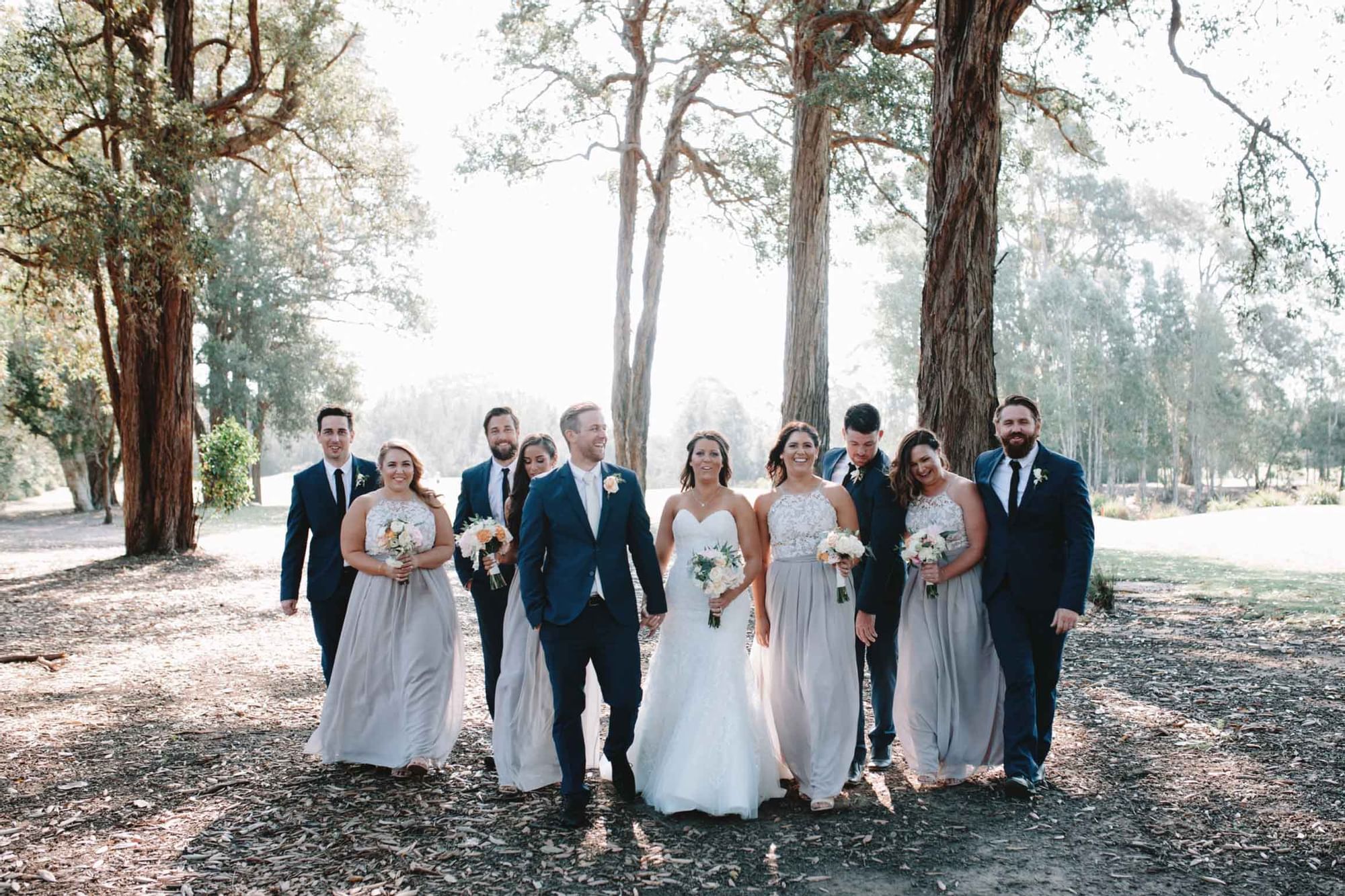 A wedding party holding bouquets standing among trees in outdoor setting at Mercure Kooindah Waters