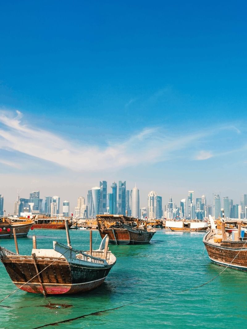 Doha Corniche with Wooden boats floating on turquoise water by a modern city skyline near Warwick Doha Hotel