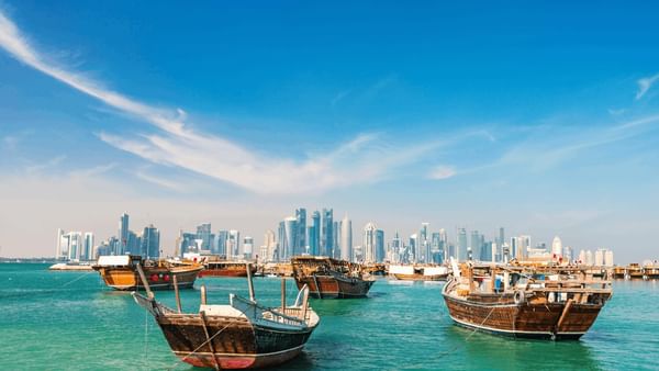 Doha Corniche with Wooden boats floating on turquoise water by a modern city skyline near Warwick Doha Hotel