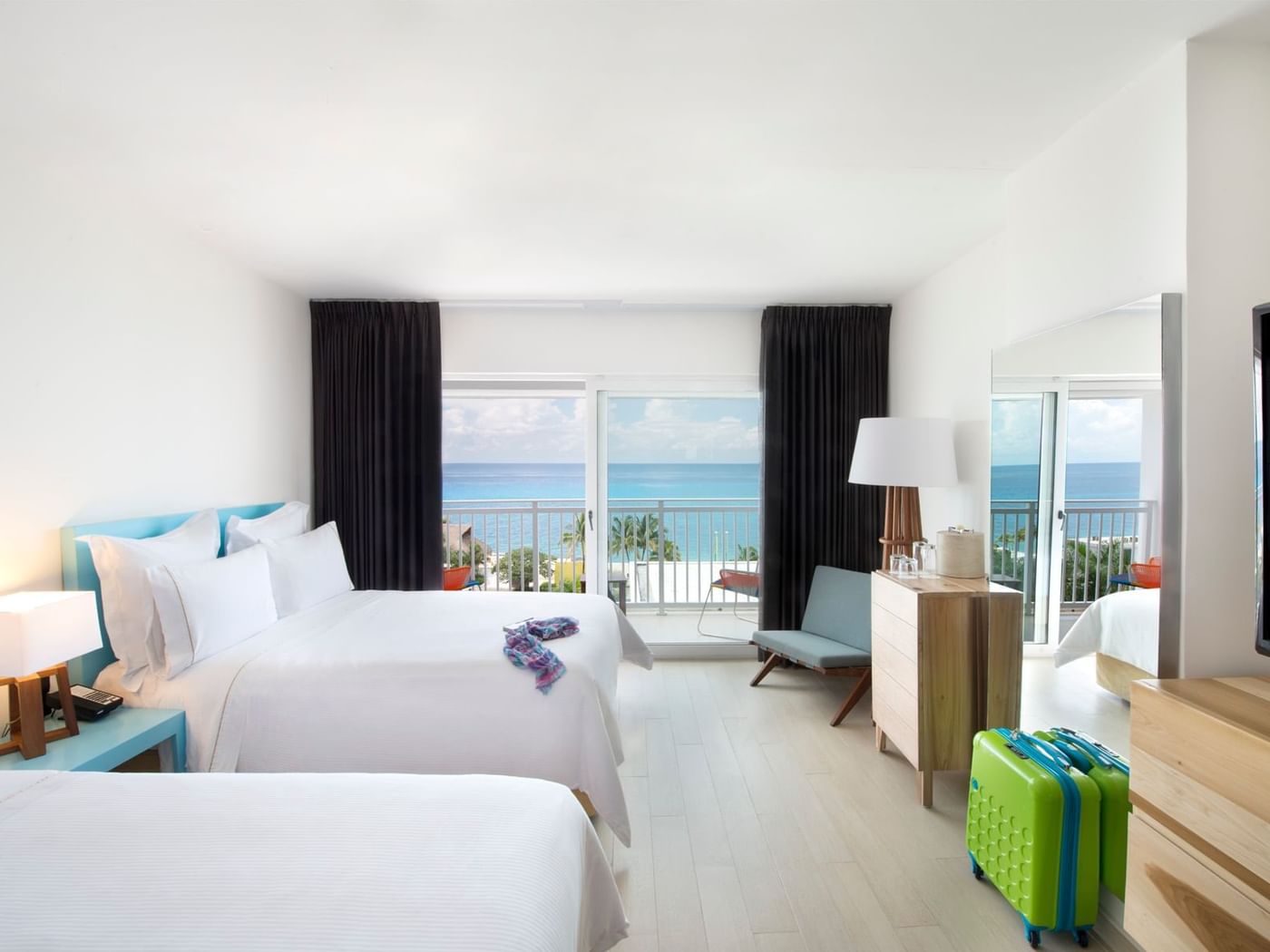 2 Bedrooms Family Suite featuring two beds, a suitcase, and a balcony with stunning ocean views at Fiesta Americana