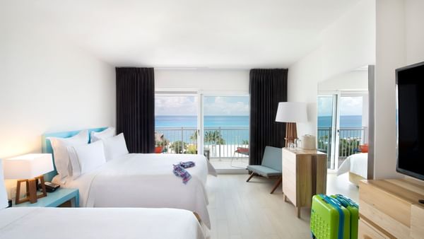 2 Bedrooms Family Suite featuring two beds, a suitcase, and a balcony with stunning ocean views at Fiesta Americana