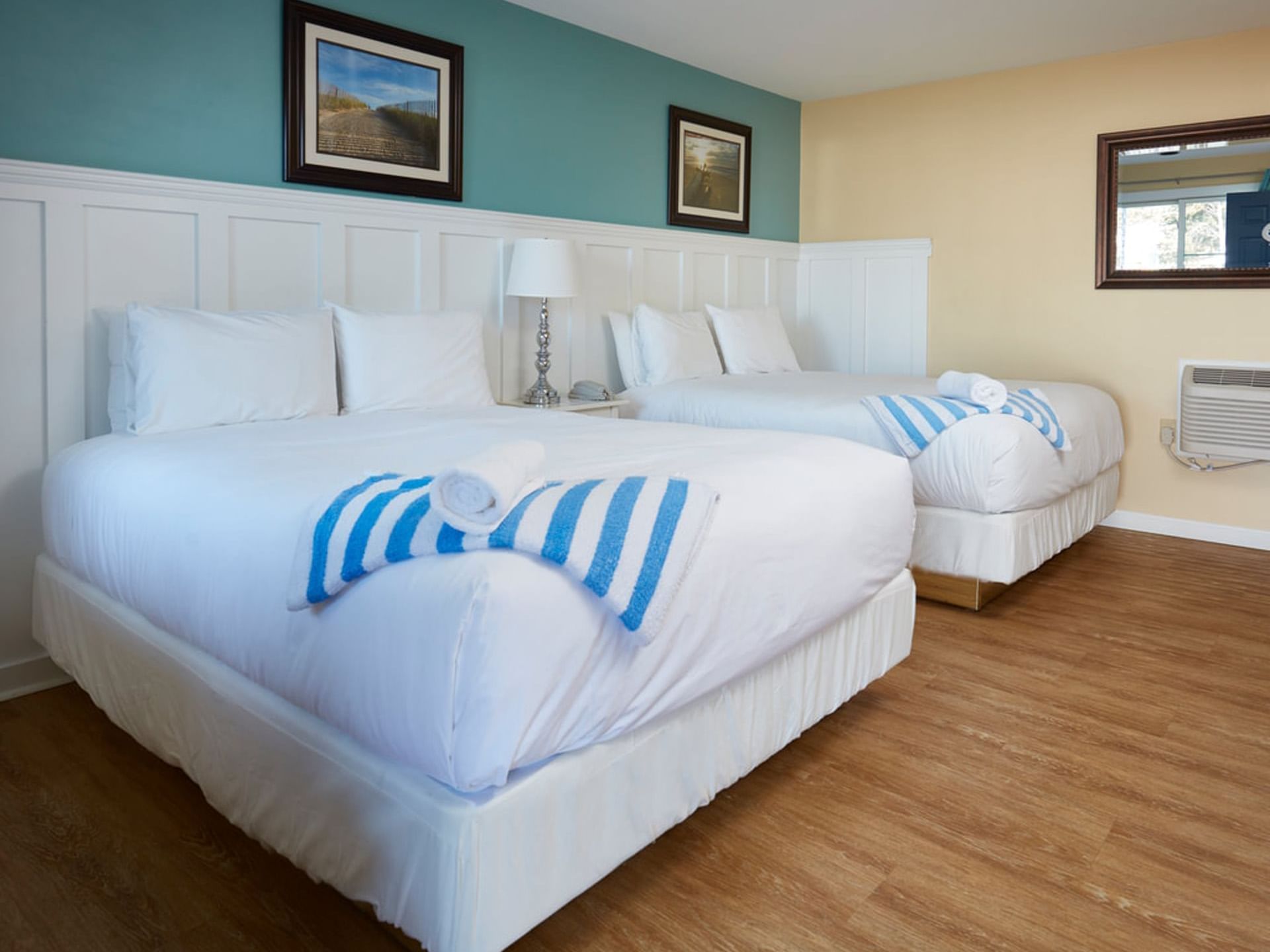 Two beds with table lamp and wooden floors in Two Queen at Breezeway Boutique Hotel