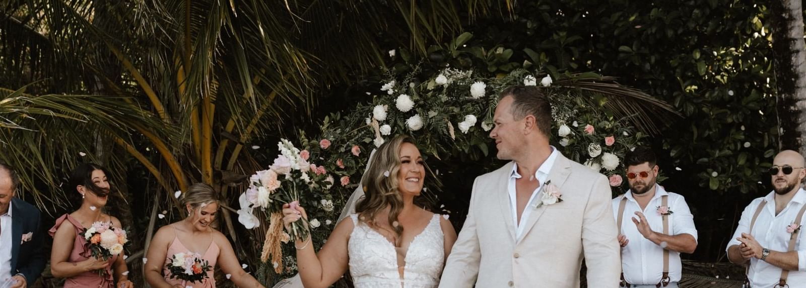 Beach wedding with couple walking on sand & flower petals scattered around at Pullman Port Douglas Sea Temple Resort & Spa