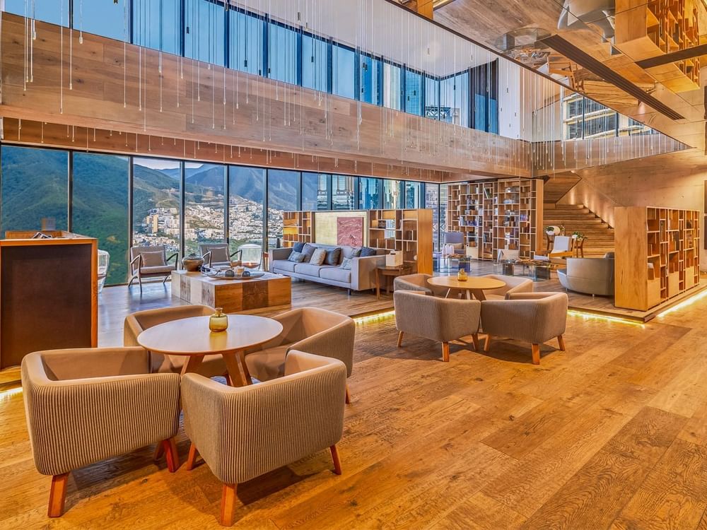 Lobby area with coffee tables, comfy chairs, shelves & chandeliers at Live Aqua Resorts and Residence Club