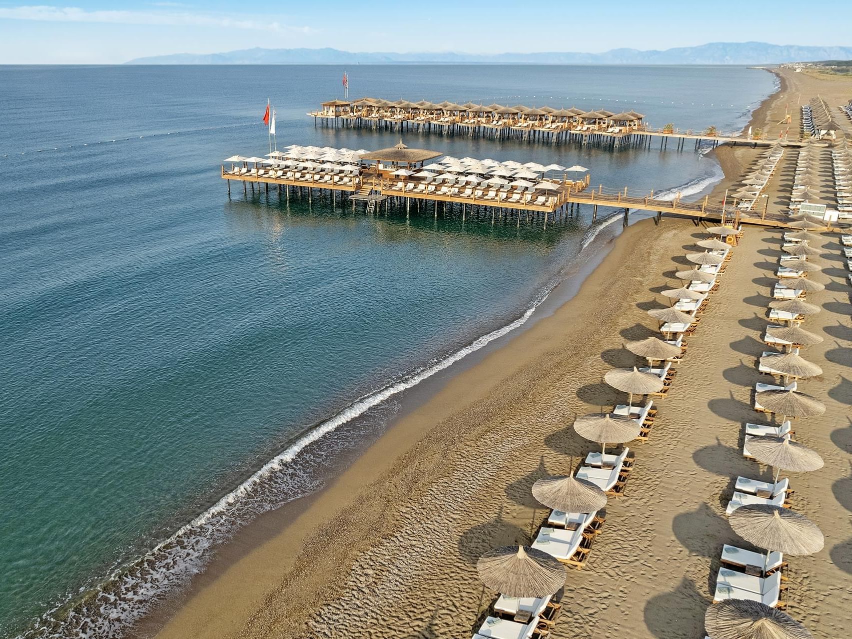 Aerial view of Titanic Deluxe Golf Belek with lined beach umbrellas, and piers