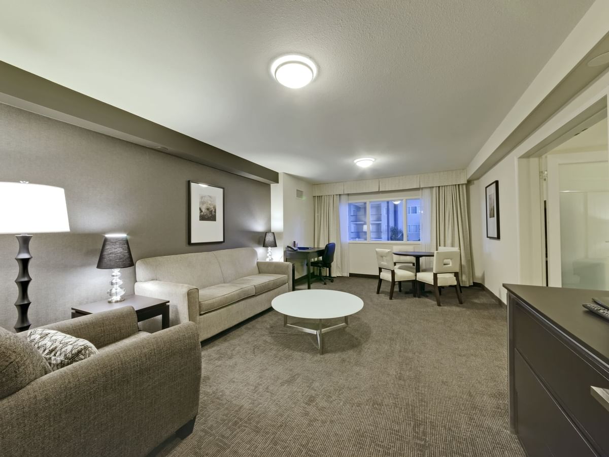 Living area of guest room with couches, tv and table