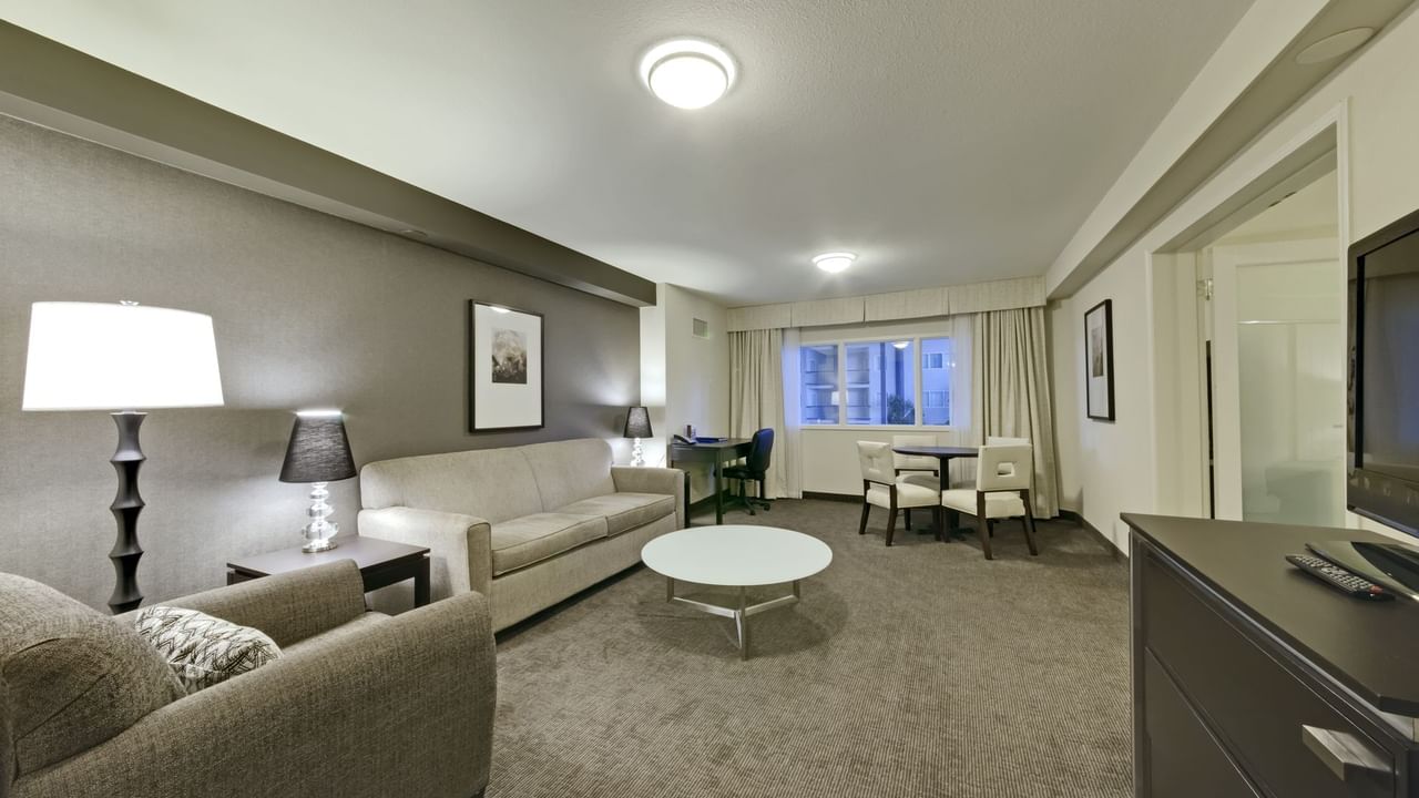 Living area of guest room with couches, tv and table