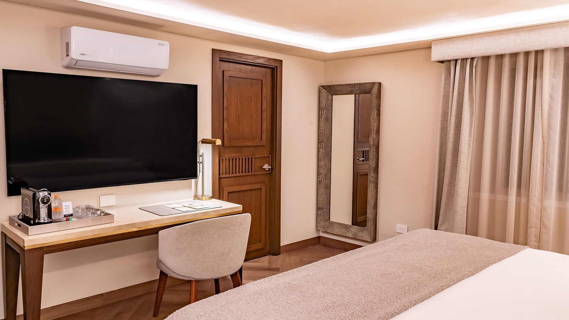 Queen New Class workspace with a wall-mounted TV, wooden door, and a tall full-length mirror at Quinta Real Puebla