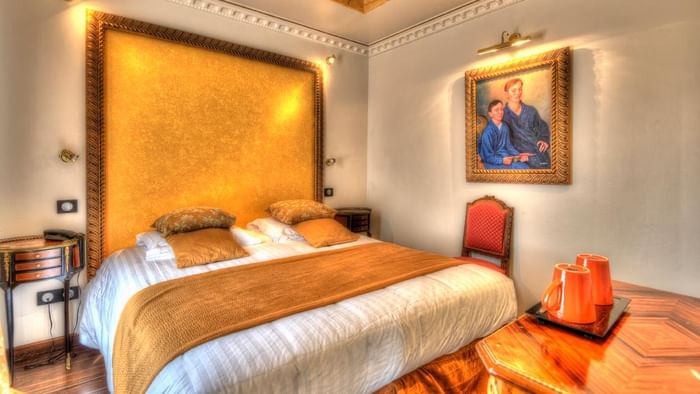 Chambre élégante avec un grand lit, une table, une chaise et un tableau à l'Hôtel Villa Aultia.