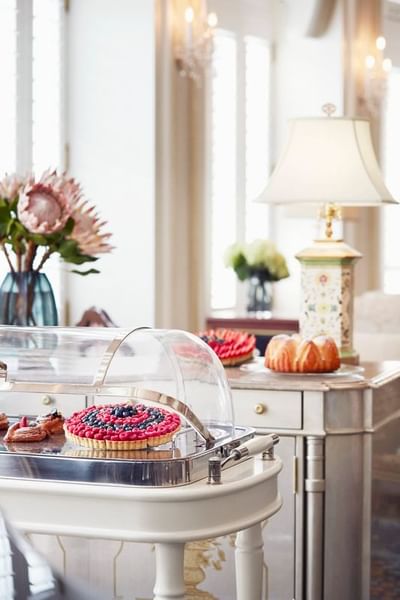Elegant dessert display featuring a fruit tart, pastries, and decorative flowers in Park Lounge at Park Hyatt Saigon