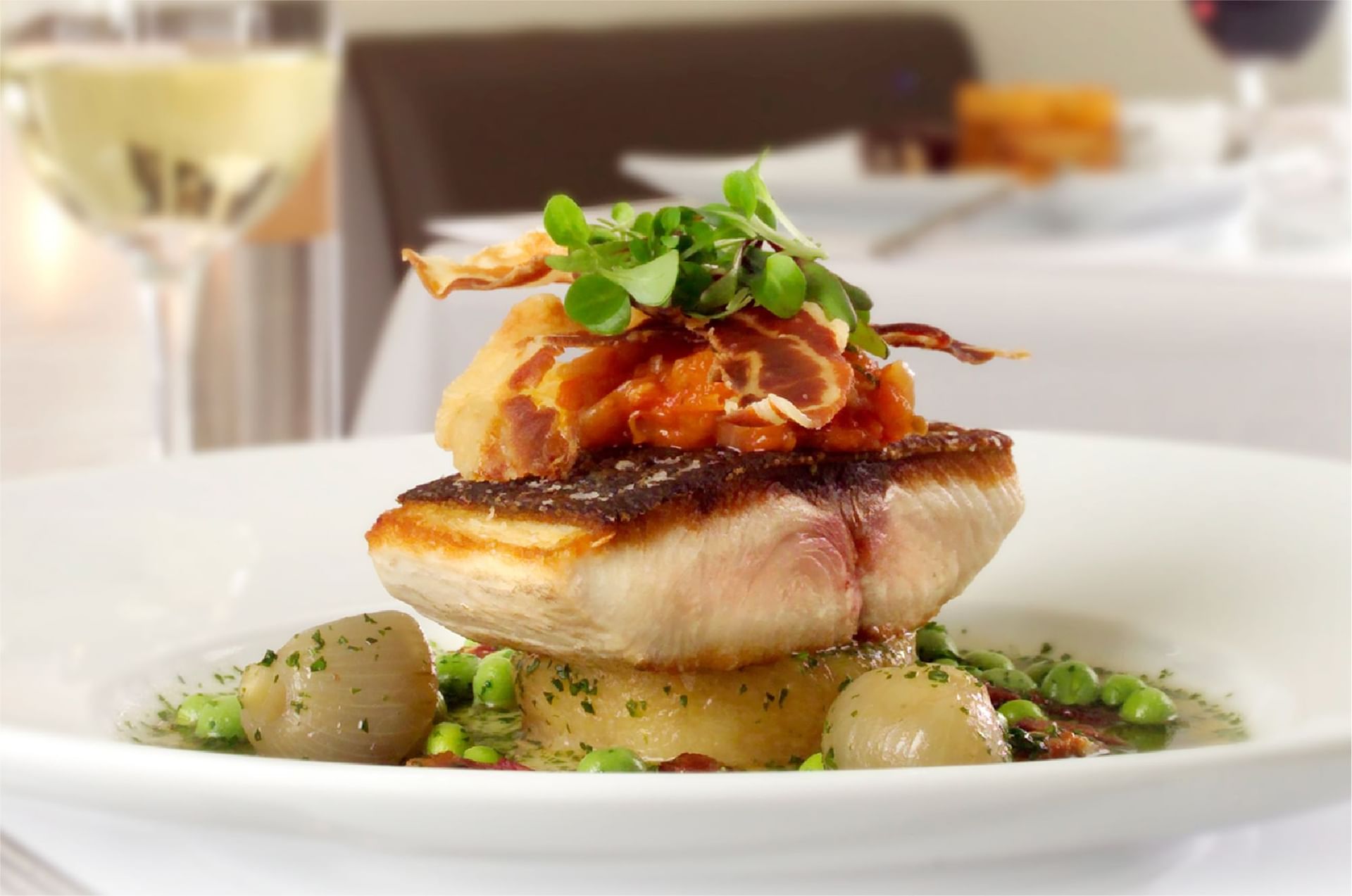 Close-up of seared fish topped with crispy prosciutto, served at Senja, The Saujana Hotel Kuala Lumpur