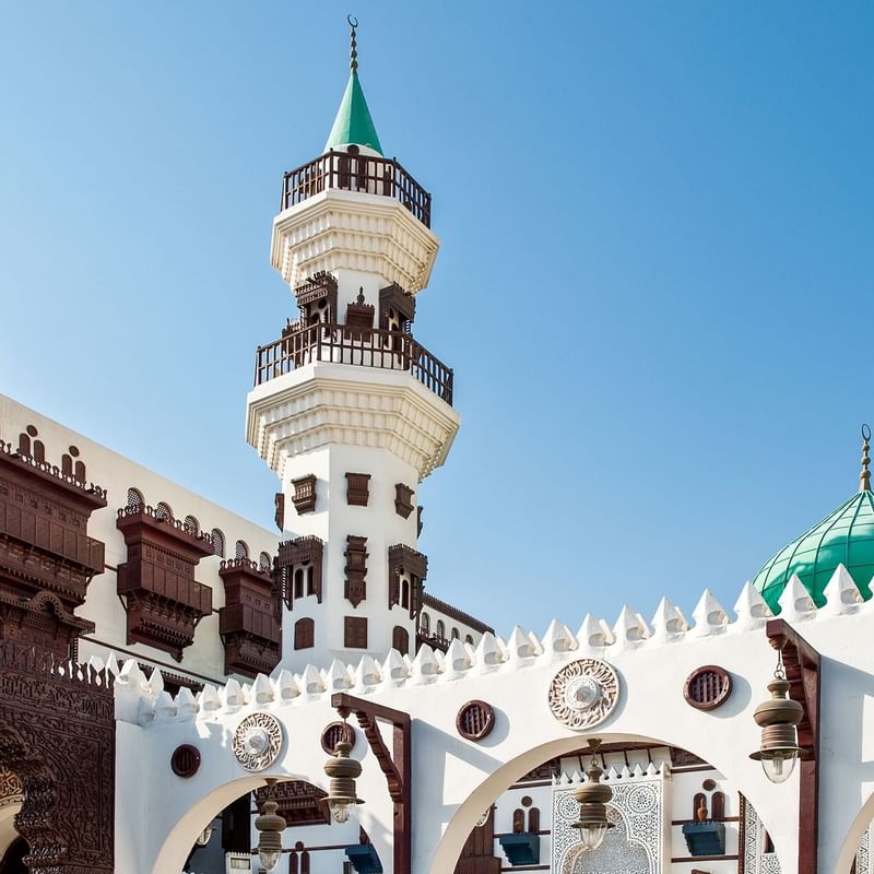 Stunning view of Jeddah mosque featuring a green dome, and intricate wooden balconies, near Warwick Hotels and Resorts