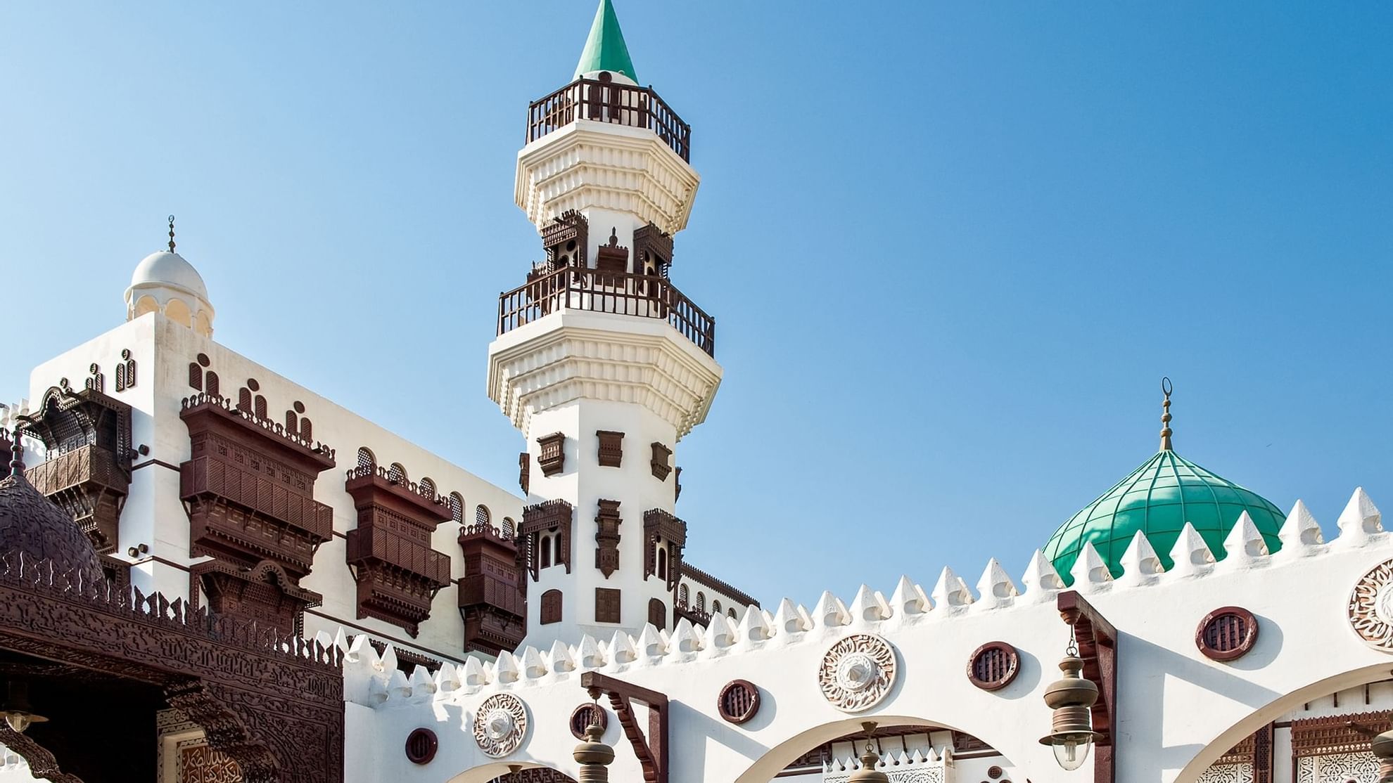 Stunning view of Jeddah mosque featuring a green dome, and intricate wooden balconies, near Warwick Hotels and Resorts