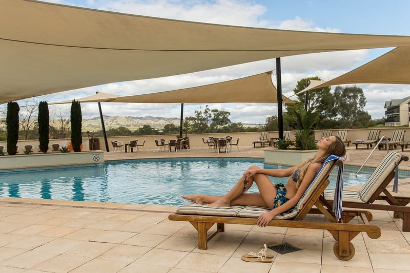 A lady relaxing in lounge chairs by the pool at Novotel Barossa