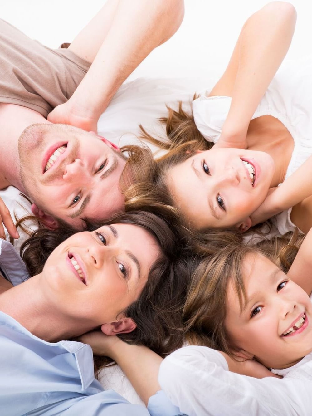 Family lying on a bed with heads together, relaxing in the guest room at Hotel Westminster Paris