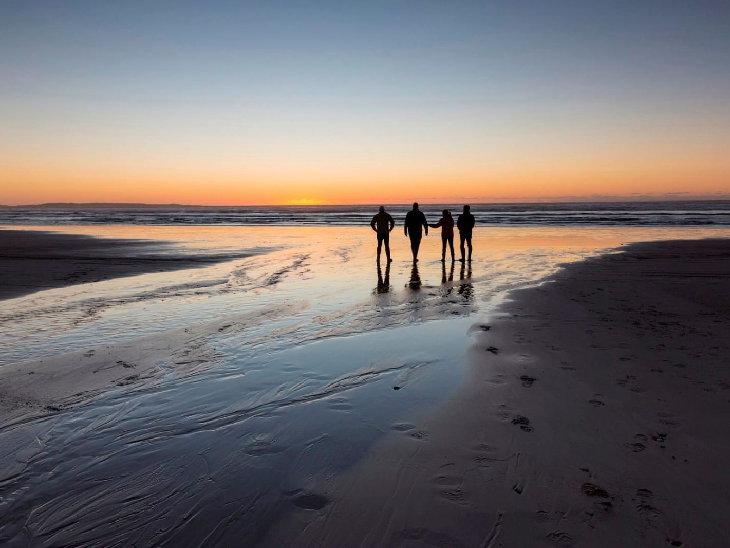 People walking on the beach at sunset near Strahan Village