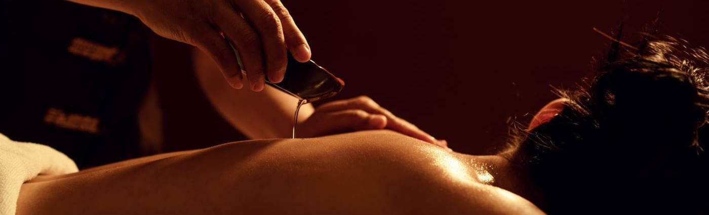 Therapist pours warm aromatic oil onto a guest\’s back during a soothing massage at May Fair Spa, The May Fair Hotel