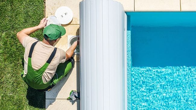 Hombre limpiando junto a la piscina al aire libre en Live Aqua Resorts