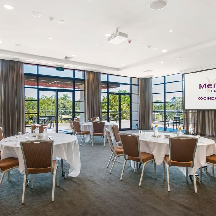 Kooindah Three conference room with tables, chairs, and large windows overlooking trees at Mercure Kooindah Waters