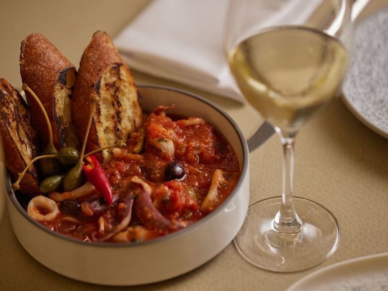Bowl of seafood stew with toasted bread & glass in Modo Mio at Crown Promenade Perth