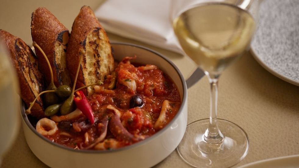 Bowl of seafood stew with toasted bread & glass in Modo Mio at Crown Promenade Perth