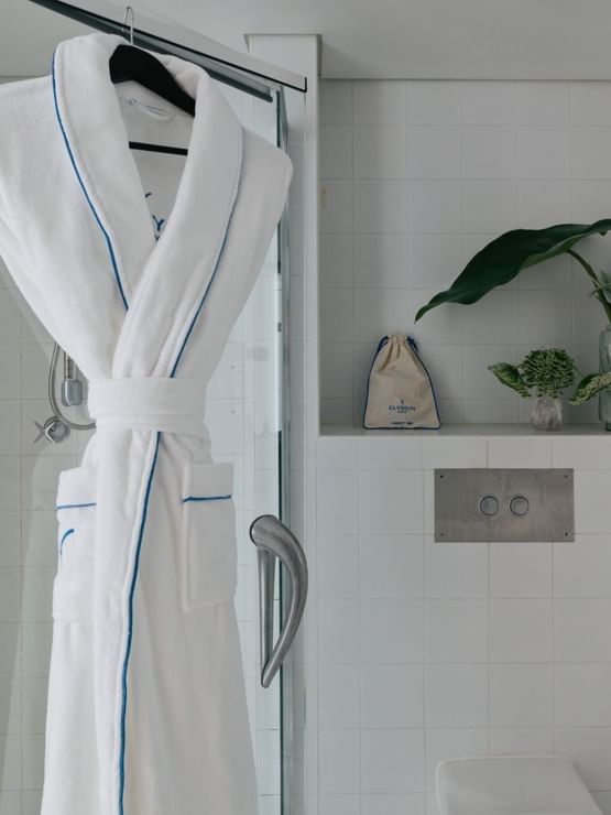 Village Twin at Elysium Manly, featuring a white robe hanging by a glass shower under greenery surrounding the ledge