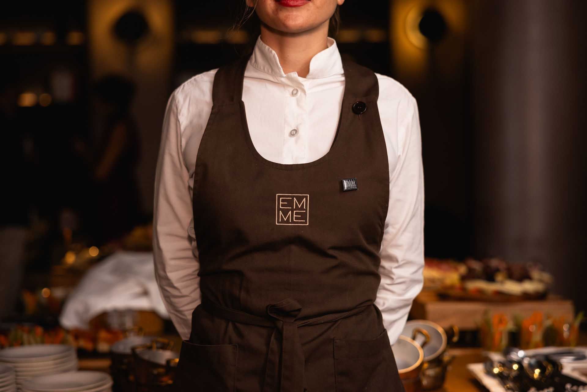 A chef in a white shirt and brown apron cooking in EMME Restaurant at Margutta 19