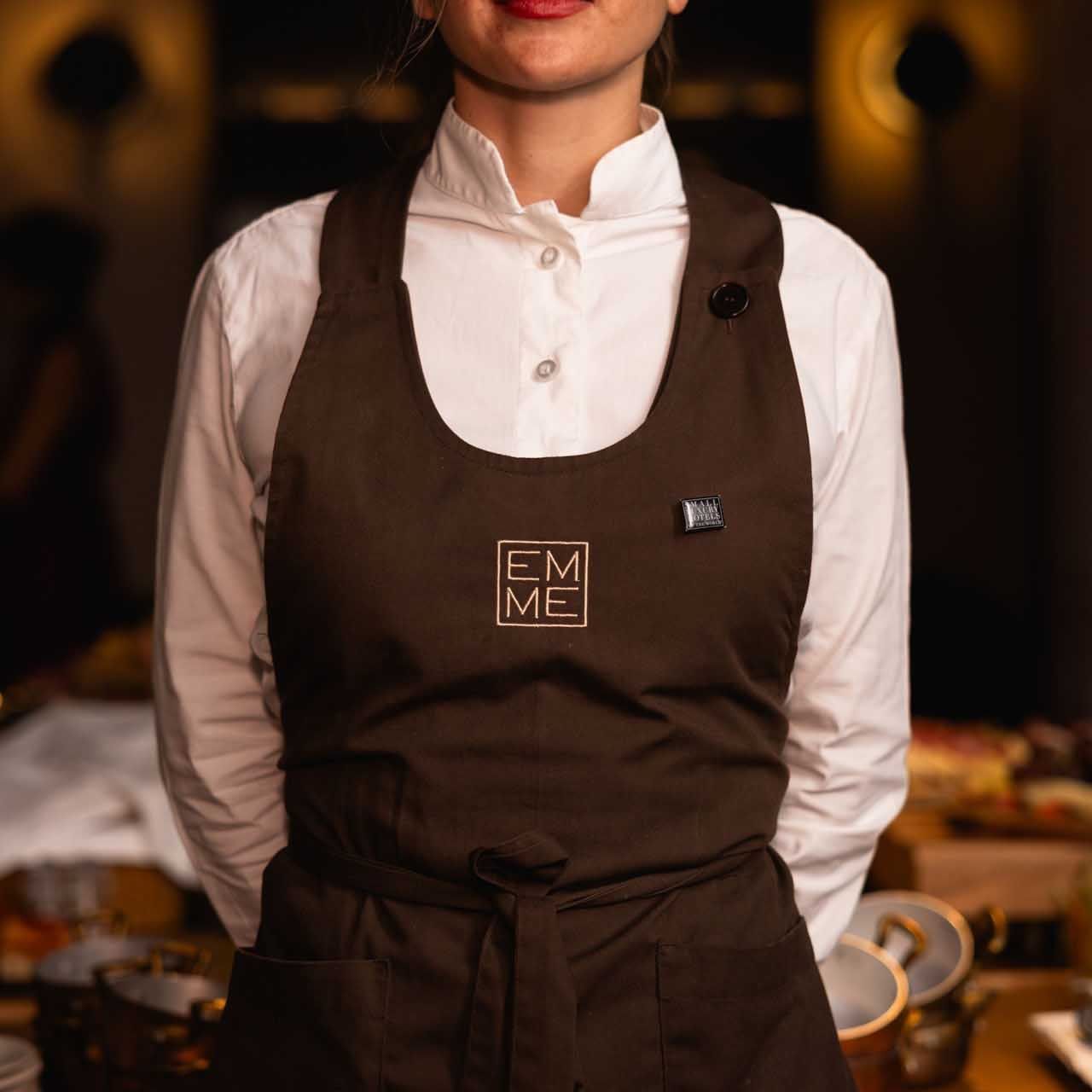 A chef in a white shirt and brown apron cooking in EMME Restaurant at Margutta 19