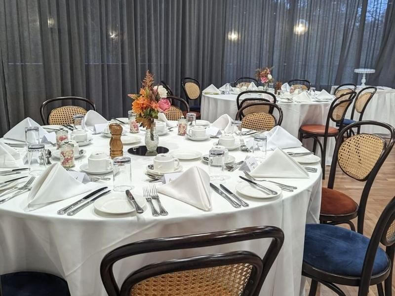 Elegant wedding setup with round tables and cane-backed chairs in the Park Room at Amora Herencia Riverwalk Melbourne