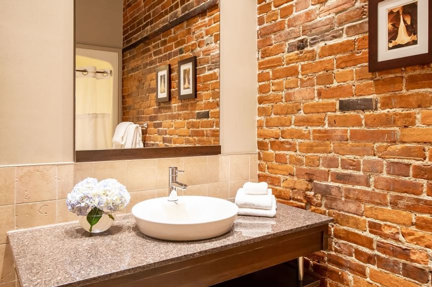 Bathroom vanity with mirror, fresh flowers & towels in Queen Premiere Midtown's bathroom at Retro Suites Hotel